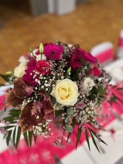 Bouquet de fleurs avec rose crème, gerberas fuchsia et gypsophile sur un chemin de table rose vif.