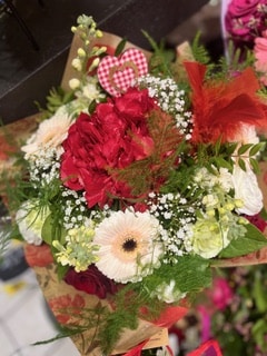 Bouquet de fleurs romantique composé de roses rouges, gerberas blancs, gypsophile et un cœur décoratif.