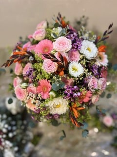 Bouquet rond romantique de roses roses, gerberas et fleurs blanches, agrémenté de feuillage d'eucalyptus.