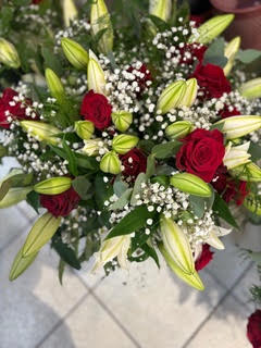 Bouquet de roses rouges, boutons de lys blancs et gypsophile blanche pour une composition florale romantique.