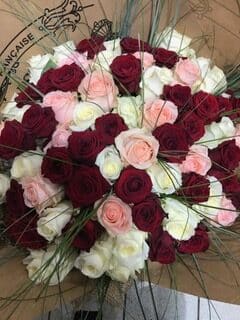 Bouquet romantique de roses rouges, roses et blanches dans un emballage kraft marqué Française.