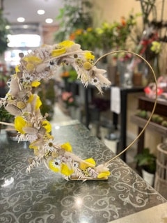 Cœur romantique en fleurs séchées jaunes et blanches sur socle doré pour une décoration bohème élégante.