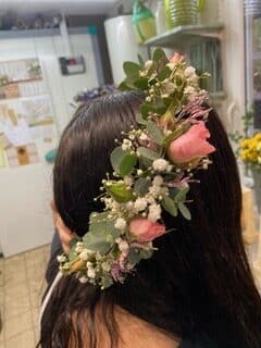 Accessoire de coiffure en fleurs fraîches, roses roses et eucalyptus sur cheveux bruns.
