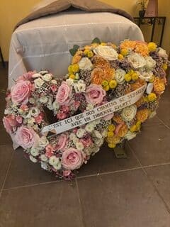 Double cœur de fleurs roses et jaunes avec ruban 'C’est ici que nos chemins se séparent avec un immense regret'.
